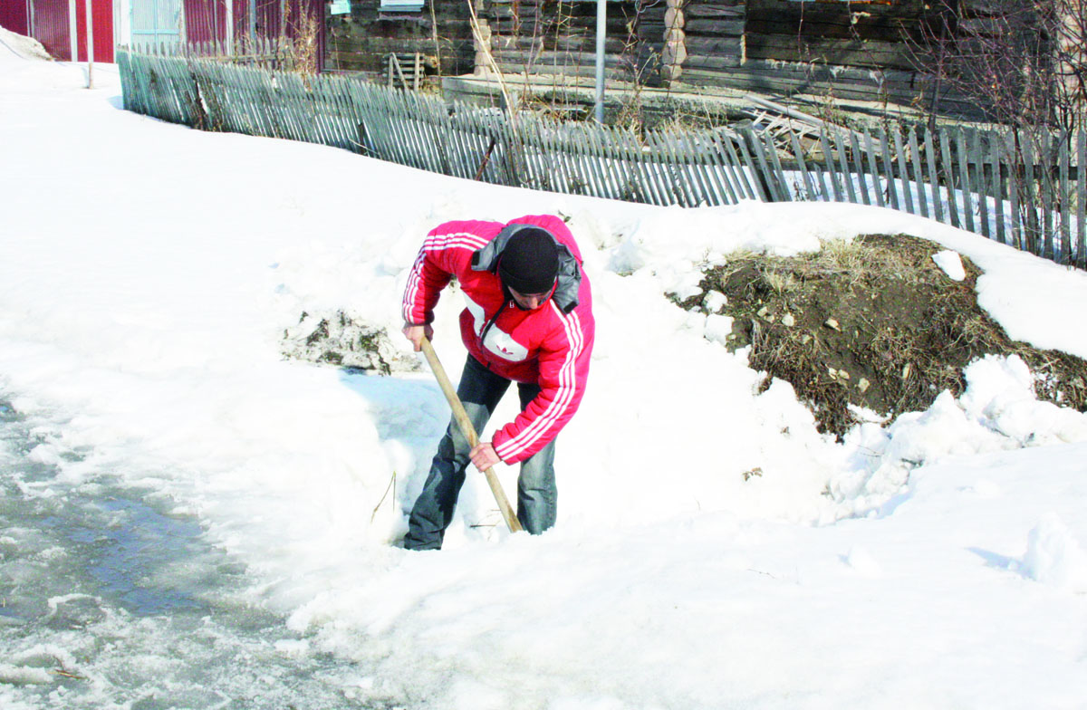 На фото сотрудник администрации поселения Сергей Чешко прочищает кювет от снега и наледи